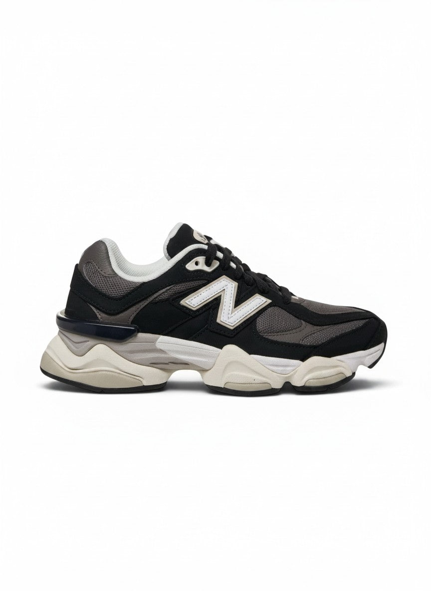 Tenis New Balance 9060 negros y grises para hombre, con detalles blancos y suela gruesa de goma.
