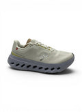 Tenis On Cloud Cloudsurfr Next blancos y grises para mujer, con detalles amarillos y suela de goma. Diseño moderno para uso deportivo y diario.