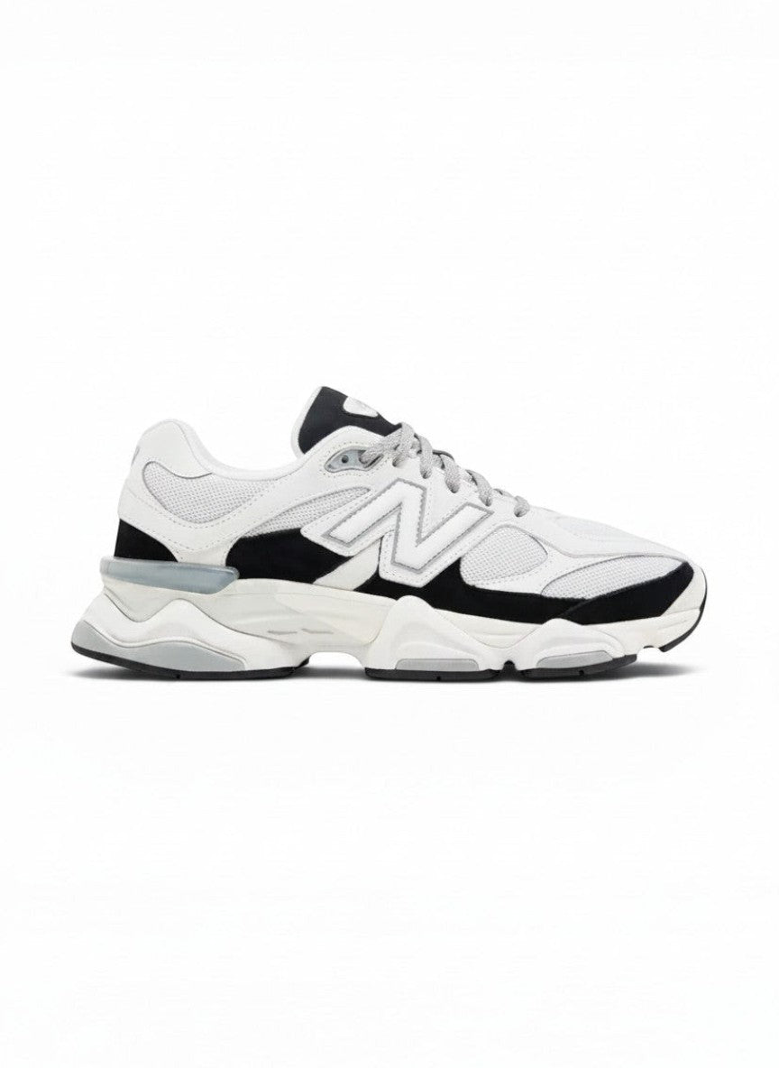 Zapatillas deportivas blancas y negras New Balance 9060 para hombre, con detalles grises y suela gruesa. Estilo urbano y cómodo.